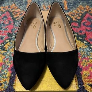 Classic black flats. A pointed toe and asymmetrical topline lend a modern touch.
